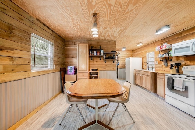 dining area featuring wood walls, sink, and light wood-type flooring