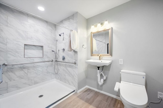 bathroom with toilet, a tile shower, and hardwood / wood-style flooring