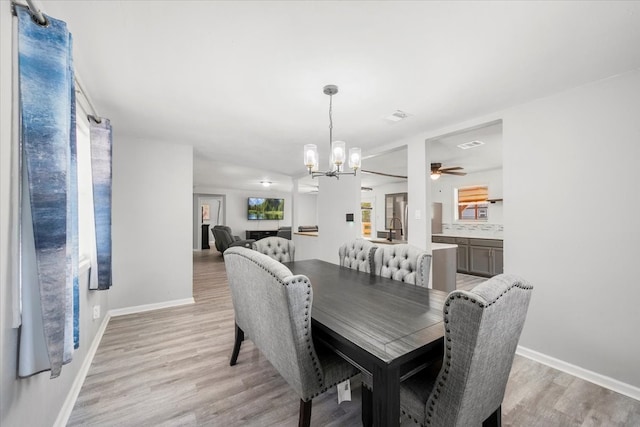 dining area with light wood-type flooring and ceiling fan with notable chandelier