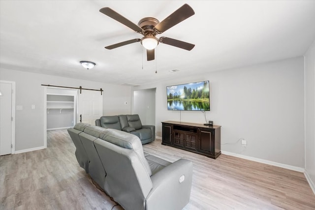 living room featuring light hardwood / wood-style floors, a barn door, and ceiling fan