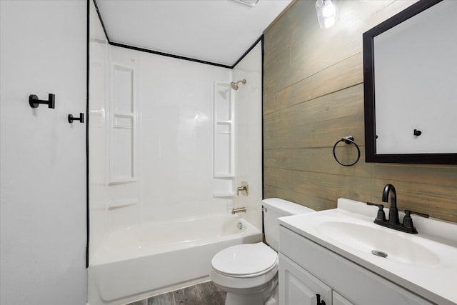 full bathroom with wood walls, toilet, vanity, hardwood / wood-style flooring, and bathing tub / shower combination