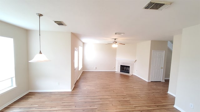 unfurnished living room featuring ceiling fan, a fireplace, and light hardwood / wood-style floors