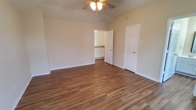 unfurnished bedroom featuring hardwood / wood-style floors, vaulted ceiling, ceiling fan, sink, and ensuite bathroom