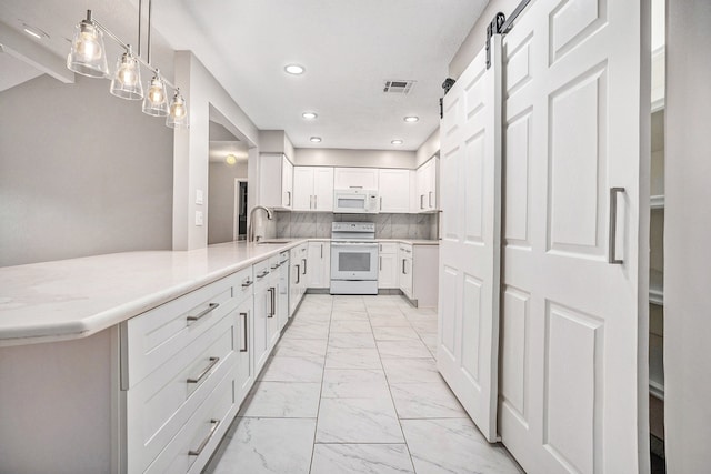 kitchen featuring white cabinetry, a barn door, pendant lighting, white appliances, and decorative backsplash