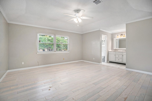 unfurnished bedroom with a textured ceiling, ceiling fan, crown molding, light hardwood / wood-style flooring, and connected bathroom