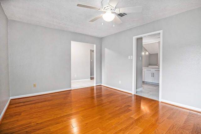 empty room with a textured ceiling, light wood-type flooring, and ceiling fan