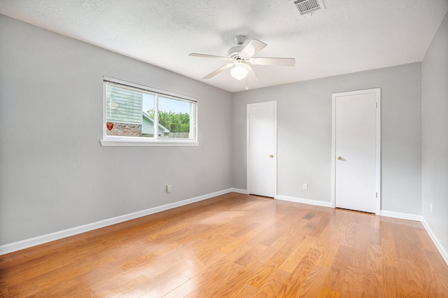 unfurnished bedroom featuring ceiling fan, light wood-type flooring, and a textured ceiling