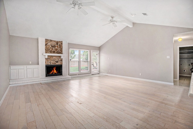 unfurnished living room with vaulted ceiling with beams, light hardwood / wood-style floors, a stone fireplace, and ceiling fan