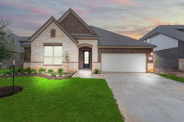 french provincial home featuring a garage and a lawn