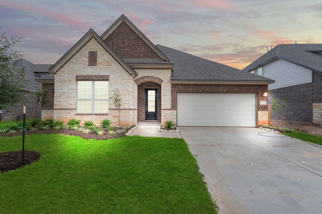 french provincial home featuring a garage and a yard