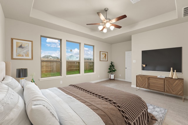 carpeted bedroom featuring ceiling fan and a raised ceiling