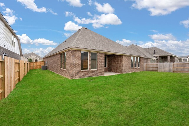 rear view of house featuring a yard, central AC unit, and a patio area