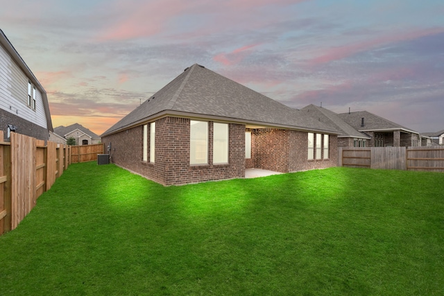 back house at dusk with a yard and a patio area