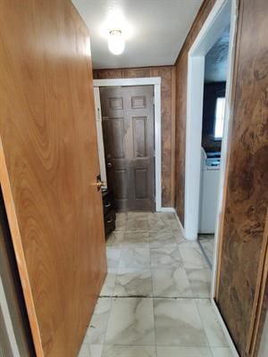 corridor featuring washer / clothes dryer and light tile patterned floors