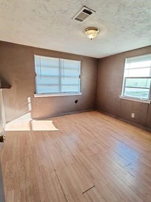 empty room with light hardwood / wood-style flooring and a textured ceiling