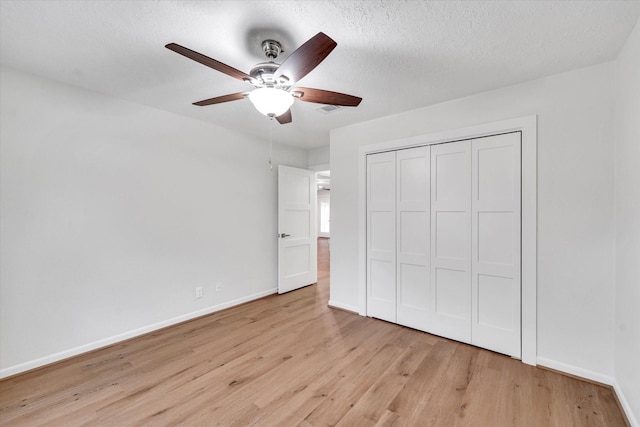 unfurnished bedroom featuring ceiling fan, a closet, light hardwood / wood-style flooring, and a textured ceiling