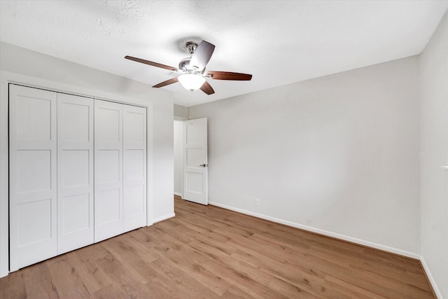 unfurnished bedroom featuring ceiling fan, light wood-type flooring, and a closet