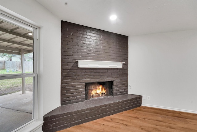 unfurnished living room featuring hardwood / wood-style flooring and a brick fireplace