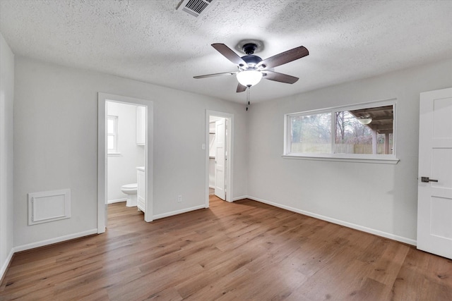 unfurnished bedroom with ceiling fan, connected bathroom, a textured ceiling, and light wood-type flooring