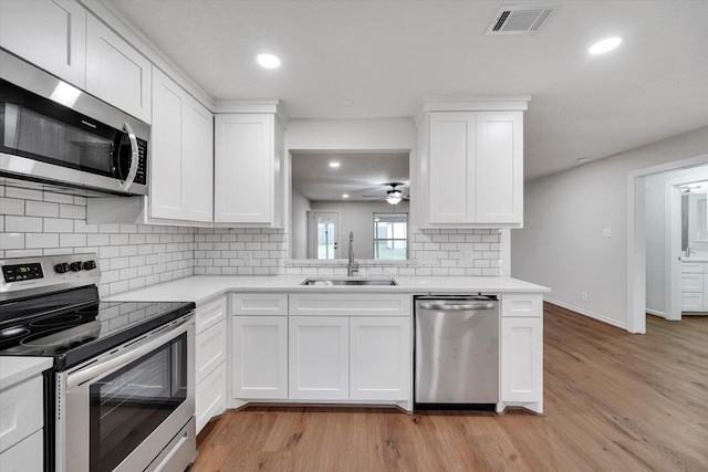 kitchen with light wood-type flooring, appliances with stainless steel finishes, sink, and white cabinets