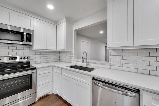 kitchen with white cabinetry, sink, dark hardwood / wood-style flooring, light stone counters, and stainless steel appliances