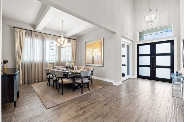 dining area with a healthy amount of sunlight, wood-type flooring, french doors, and an inviting chandelier