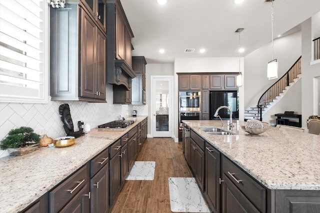 kitchen with appliances with stainless steel finishes, tasteful backsplash, sink, an island with sink, and wood-type flooring