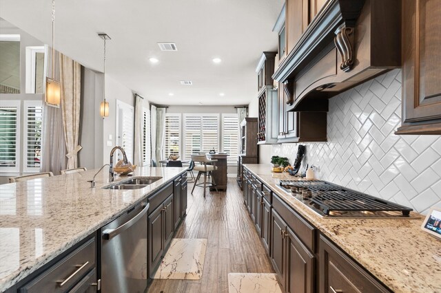 kitchen with dark brown cabinets, tasteful backsplash, stainless steel appliances, hardwood / wood-style floors, and sink