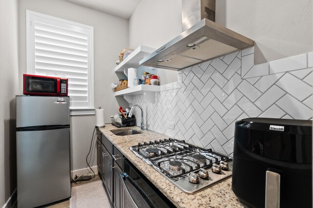 kitchen with tasteful backsplash, stainless steel appliances, sink, light stone countertops, and wall chimney exhaust hood