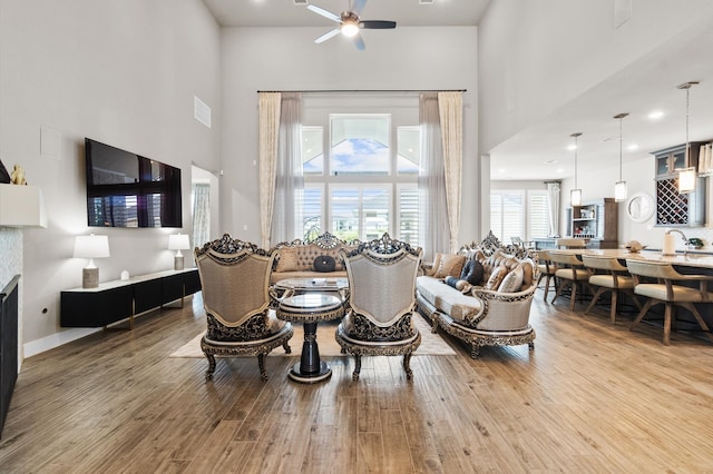 living room with sink, wood-type flooring, ceiling fan, and a high ceiling