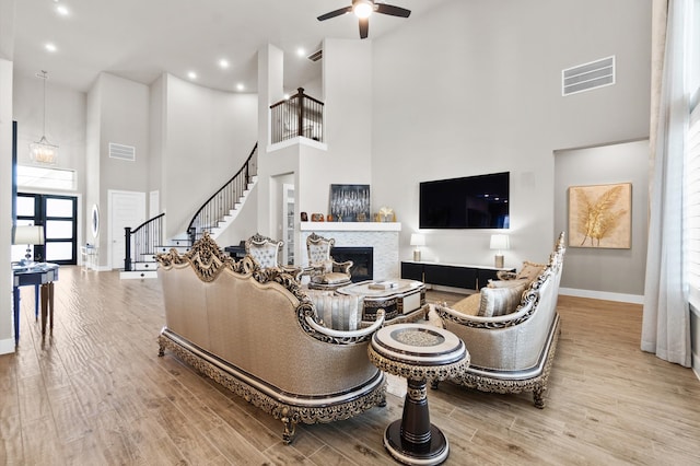 living room featuring light hardwood / wood-style flooring, ceiling fan, and a high ceiling