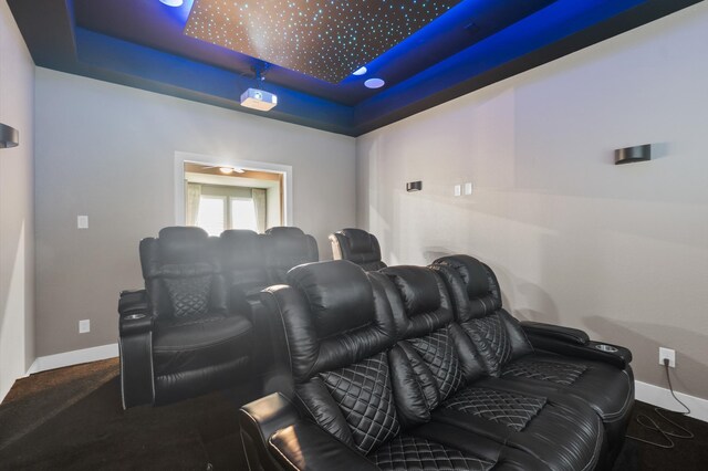 carpeted home theater with a raised ceiling