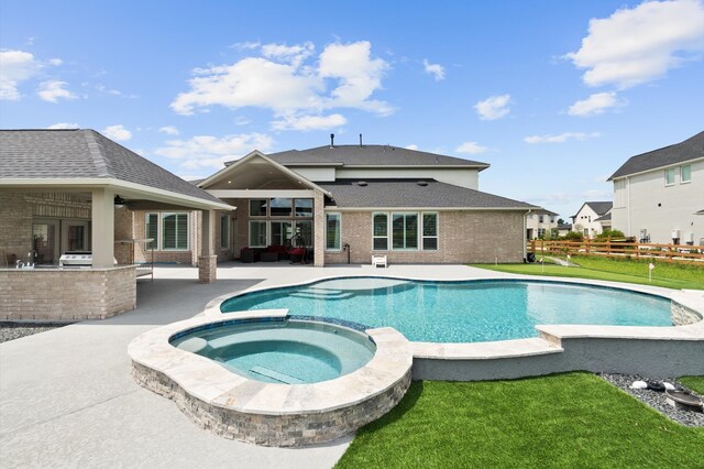 view of pool featuring exterior kitchen, a patio area, ceiling fan, an in ground hot tub, and a yard