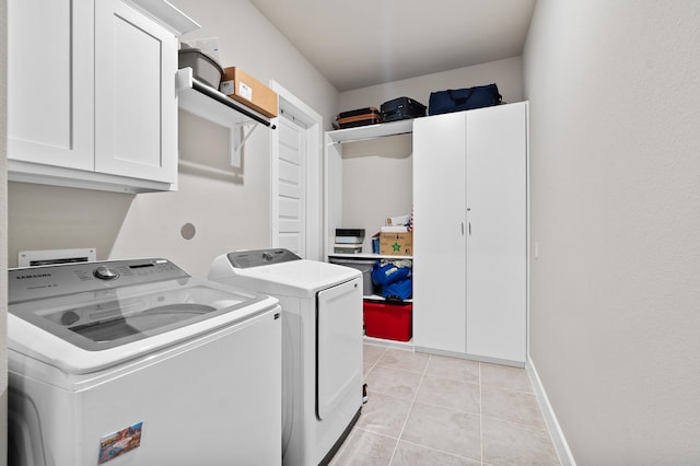 laundry room with light tile patterned floors, washing machine and dryer, and cabinets