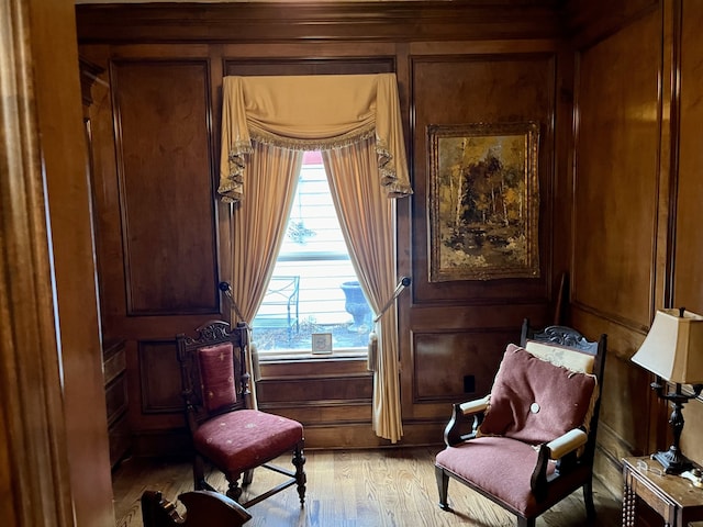 sitting room with light hardwood / wood-style floors and wood walls