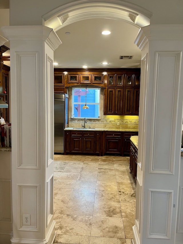 interior space featuring stainless steel built in fridge, sink, light tile patterned floors, decorative backsplash, and ornate columns