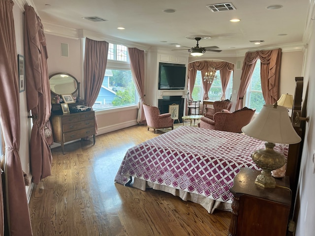 bedroom with crown molding, ceiling fan with notable chandelier, and light hardwood / wood-style floors