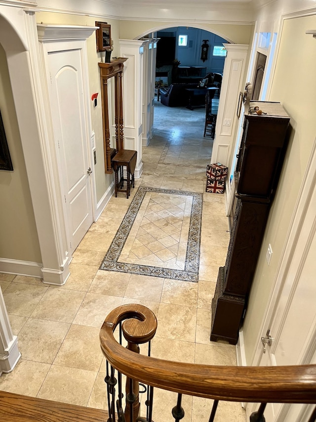 hall featuring light tile patterned floors and crown molding