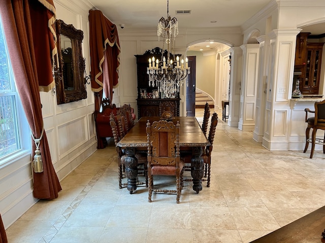 tiled dining room with decorative columns, a chandelier, and ornamental molding