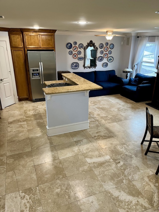 kitchen with ceiling fan, an island with sink, ornamental molding, stainless steel fridge, and light tile patterned floors