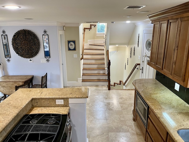 kitchen with ornamental molding, stainless steel microwave, light tile patterned floors, and light stone countertops