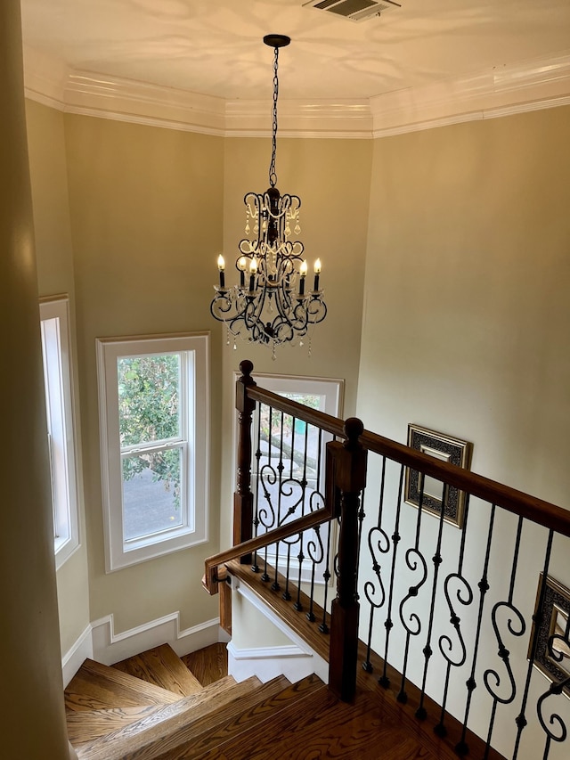 stairway with ornamental molding and a notable chandelier