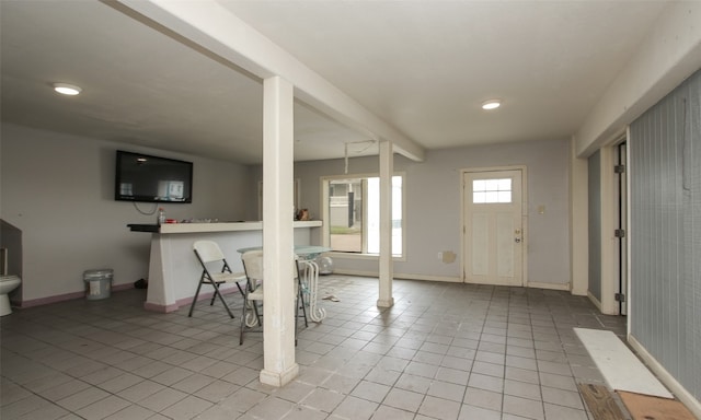 foyer entrance with beam ceiling and light tile patterned floors