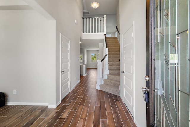 foyer entrance featuring dark hardwood / wood-style floors and a towering ceiling