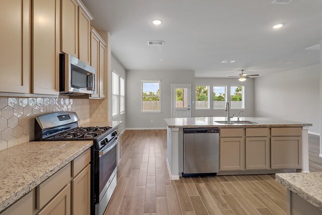 kitchen featuring ceiling fan, decorative backsplash, light wood-type flooring, sink, and appliances with stainless steel finishes