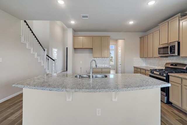 kitchen with backsplash, sink, stainless steel appliances, and a center island with sink