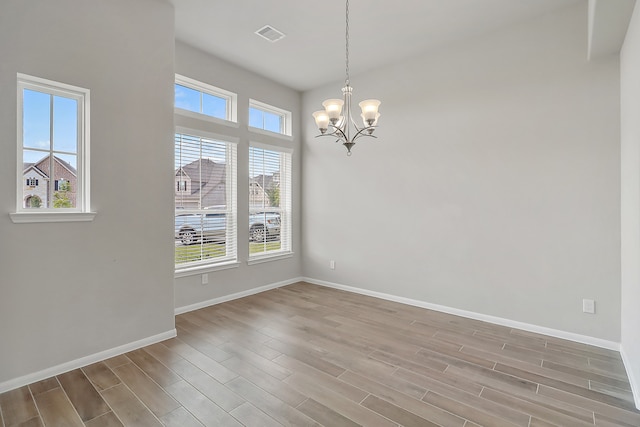 spare room with hardwood / wood-style flooring and a notable chandelier