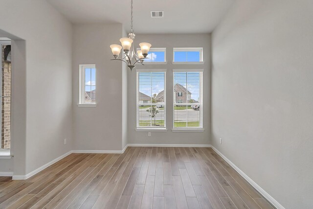 unfurnished dining area with hardwood / wood-style flooring and a notable chandelier