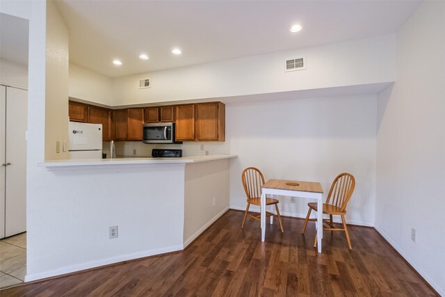 kitchen with kitchen peninsula, white fridge, and hardwood / wood-style flooring