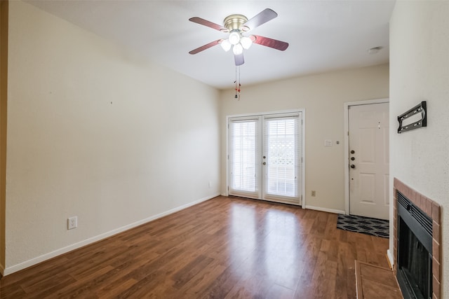 unfurnished living room with wood-type flooring, a tiled fireplace, and ceiling fan